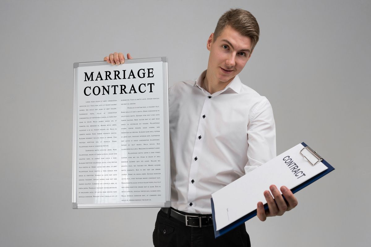 Young man holding poster with marriage contract and contract isolated on light background